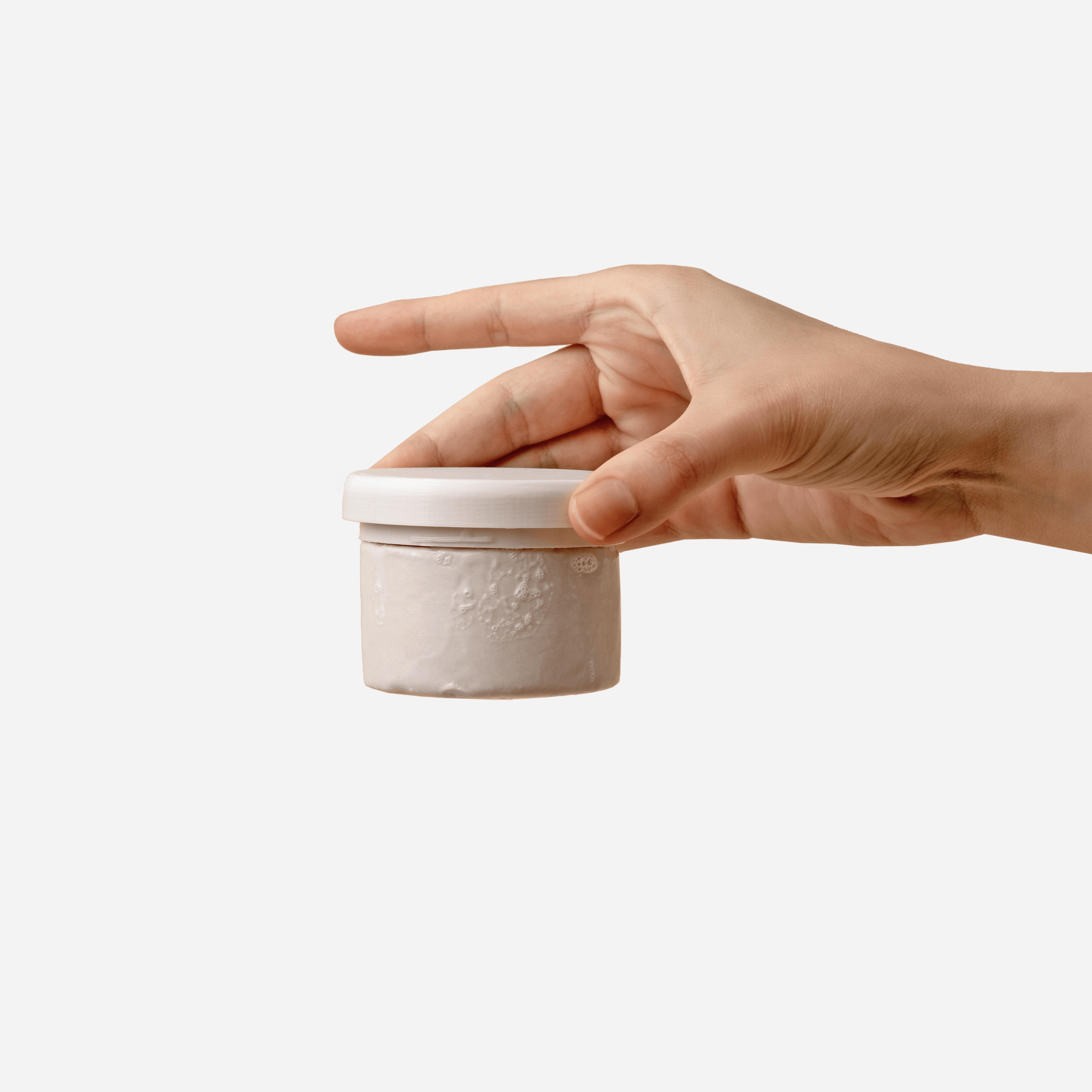 Hand holding a jar of organic cosmetics, showcasing eco-friendly and sustainable beauty products.