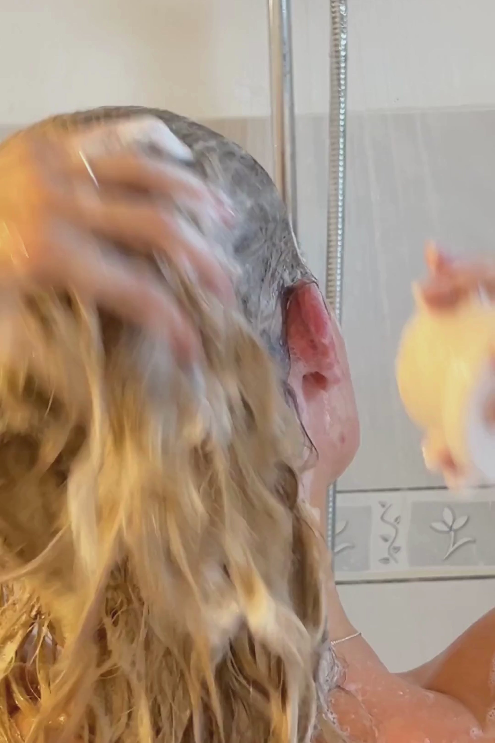 Woman lathering hair with eco-friendly solid shampoo bar in the shower, showcasing organic hair care.