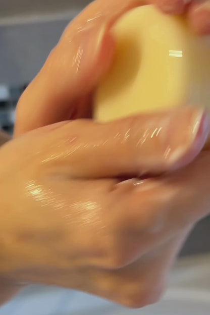 Hands holding a solid conditioner bar, showcasing its creamy texture and easy application.