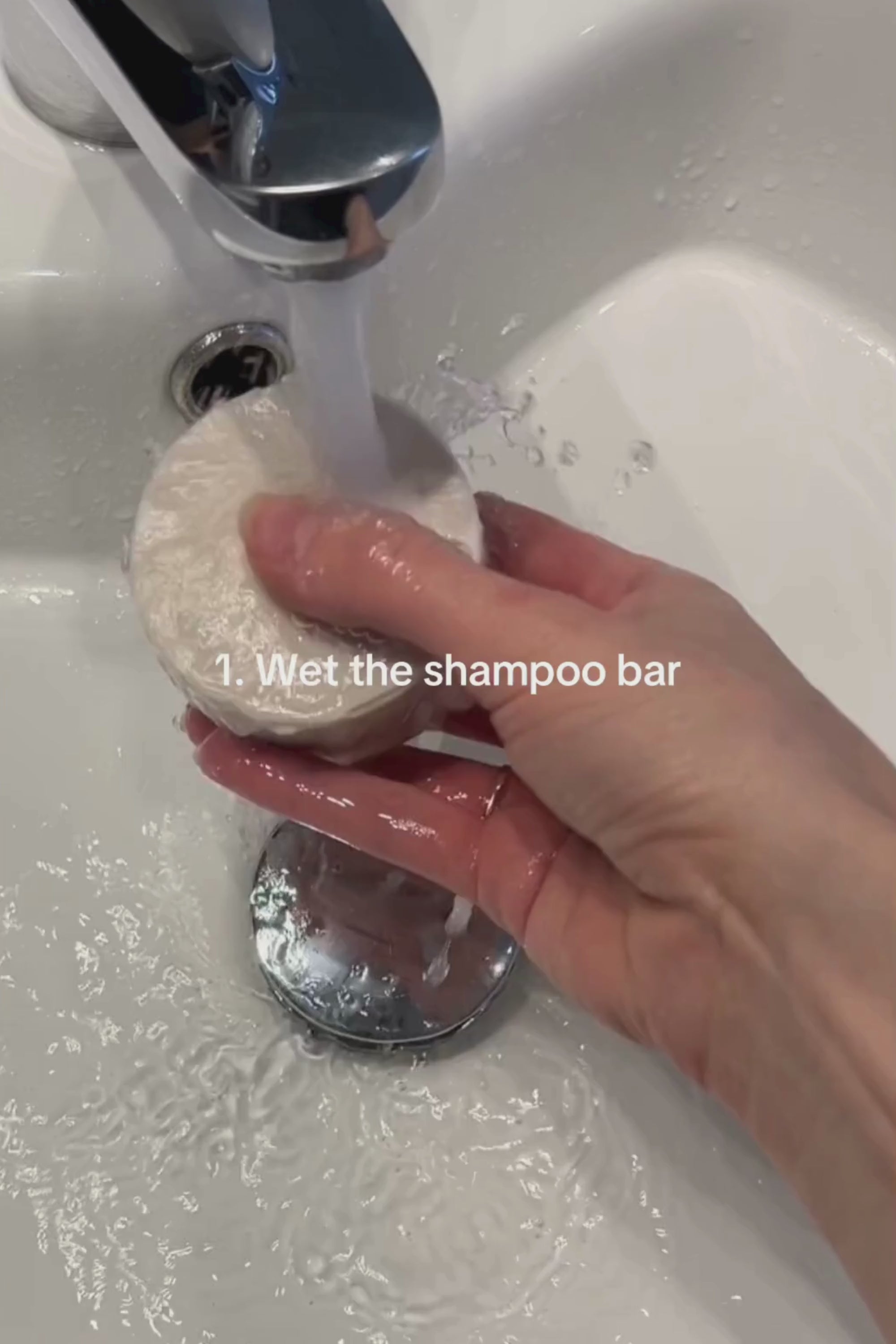 Person wetting a shampoo bar in a sink, demonstrating effective usage of eco-friendly cosmetics.